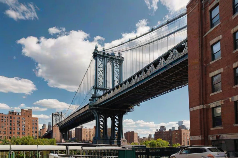 a vibrant cityscape featuring the Manhattan Bridge framed by red brick buildings under a clear blue sky with soft clouds
