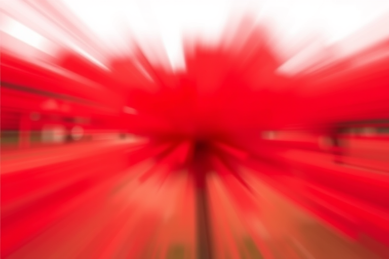 Create an abstract image with a radial blur effect in vibrant red shades, using a Canon EOS R5 camera, 24mm lens, f/2.8 aperture, ISO 100, shutter speed 1/125s, shot in portrait mode, with a smooth focus transition.