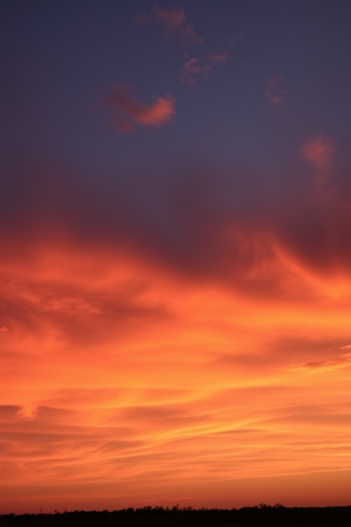 Sunset sky with vibrant clouds in shades of orange and purple, captured with a DSLR camera, 24mm lens, f/8 aperture, ISO 100, 1/200 sec, wide-angle view at golden hour.