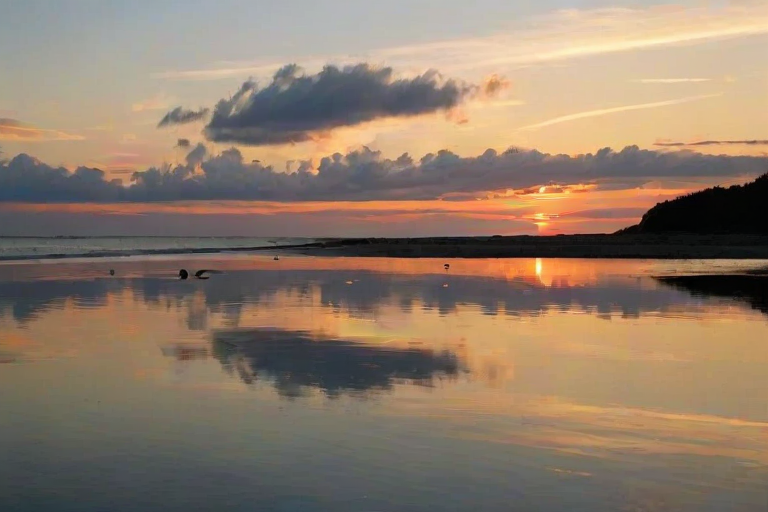 generate a serene ocean view during sunset with a golden hue and calm water reflections