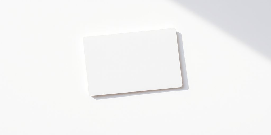 Create a high-resolution image of a blank index card lying diagonally on a white background, using a DSLR camera with a 50mm lens, aperture f/2.8, ISO 200, and a soft natural light to enhance shadows and texture.