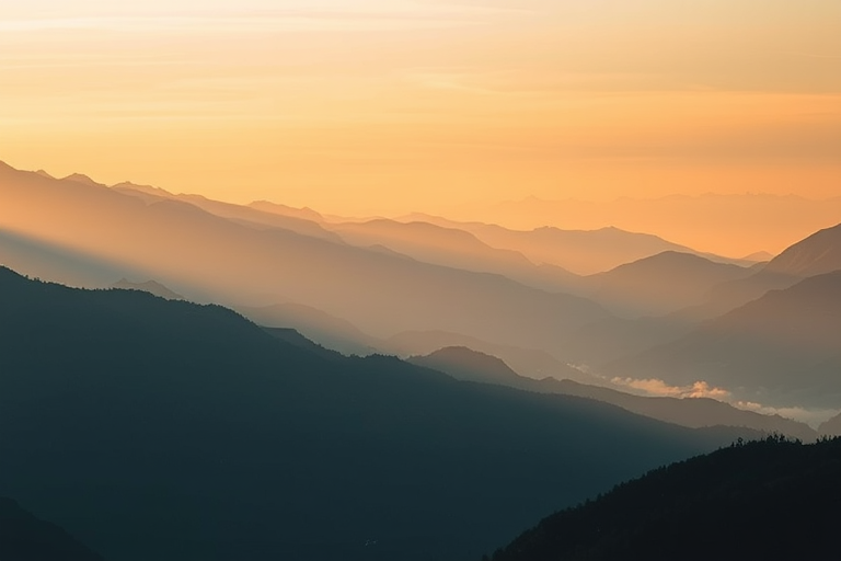 Soft-focus image of a mountain range at sunrise, soft golden light illuminating the peaks, with distant valleys filled with morning mist and a sense of quiet tranquility filling the scene.
