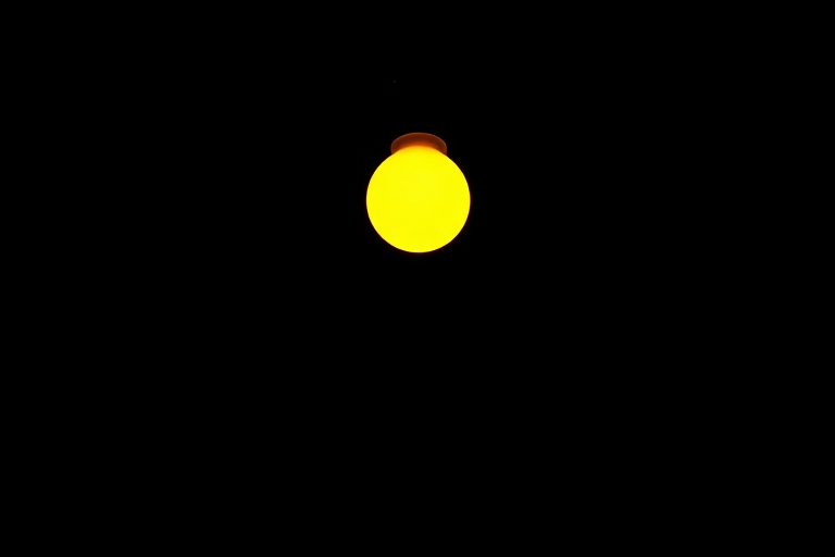 A bright yellow lamp silhouette on a solid black background, captured with a DSLR camera at f/2.8 aperture, ISO 100, 50mm lens, natural lighting, high-resolution image with a shallow depth of field and minimal noise.