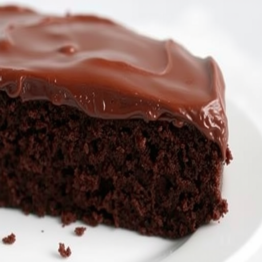 A close-up view of a slice of rich chocolate cake with a thick layer of glossy chocolate frosting on a white plate, showcasing the moist texture and deep brown color of the cake, with a soft background that highlights the dessert.