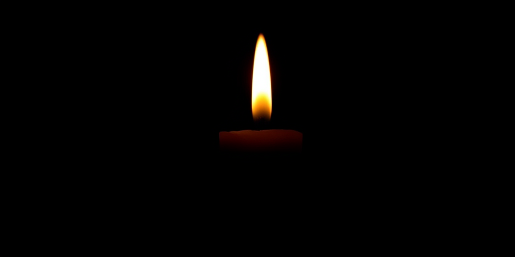 Create a high-resolution silhouette image of a candle with a flame against a black background, shot in macro view using a DSLR camera at f/2.8 aperture, ISO 100, and a shutter speed of 1/60 seconds to enhance detail and contrast.