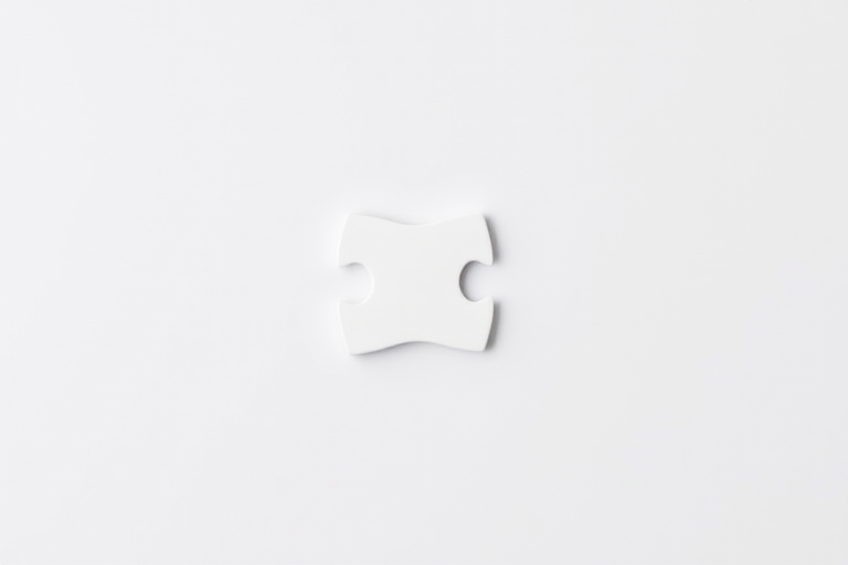 Create a high-resolution image of a single white puzzle piece on a plain background, using a Canon EOS 5D Mark IV, 50mm lens, aperture f/2.8, ISO 100, and 1/200 shutter speed for enhanced clarity and detail.