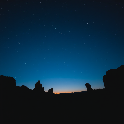 Capture a serene twilight landscape silhouette with rocky formations against a deep blue sky filled with stars, using a DSLR camera at ISO 800, f/4.0 aperture, 15-second exposure, and a wide-angle lens at 18mm for enhanced clarity and depth.