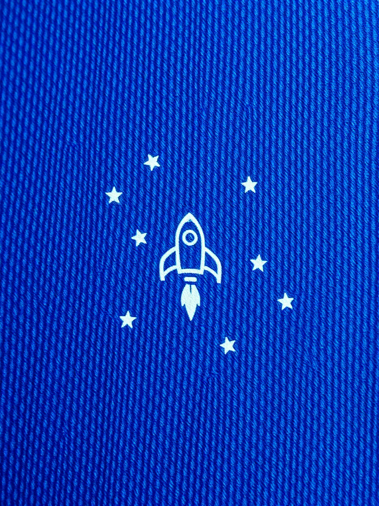 regenerate a textured blue fabric featuring a rocket and stars, macro view, f-stop 2.8, shutter speed 1/60, ISO 100, natural light, DSLR camera