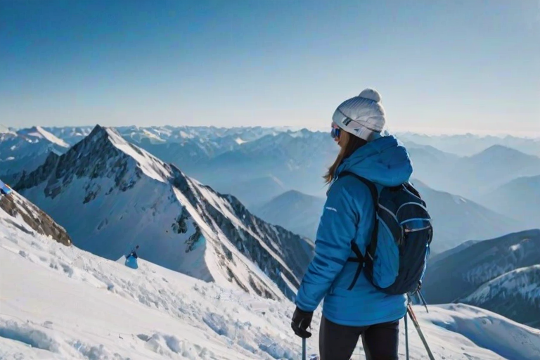 Snow-covered mountains, the sky a brilliant blue, a woman in a puffy jacket stands at the top of a ridge, her skis planted in the snow as she takes in the stunning view below.