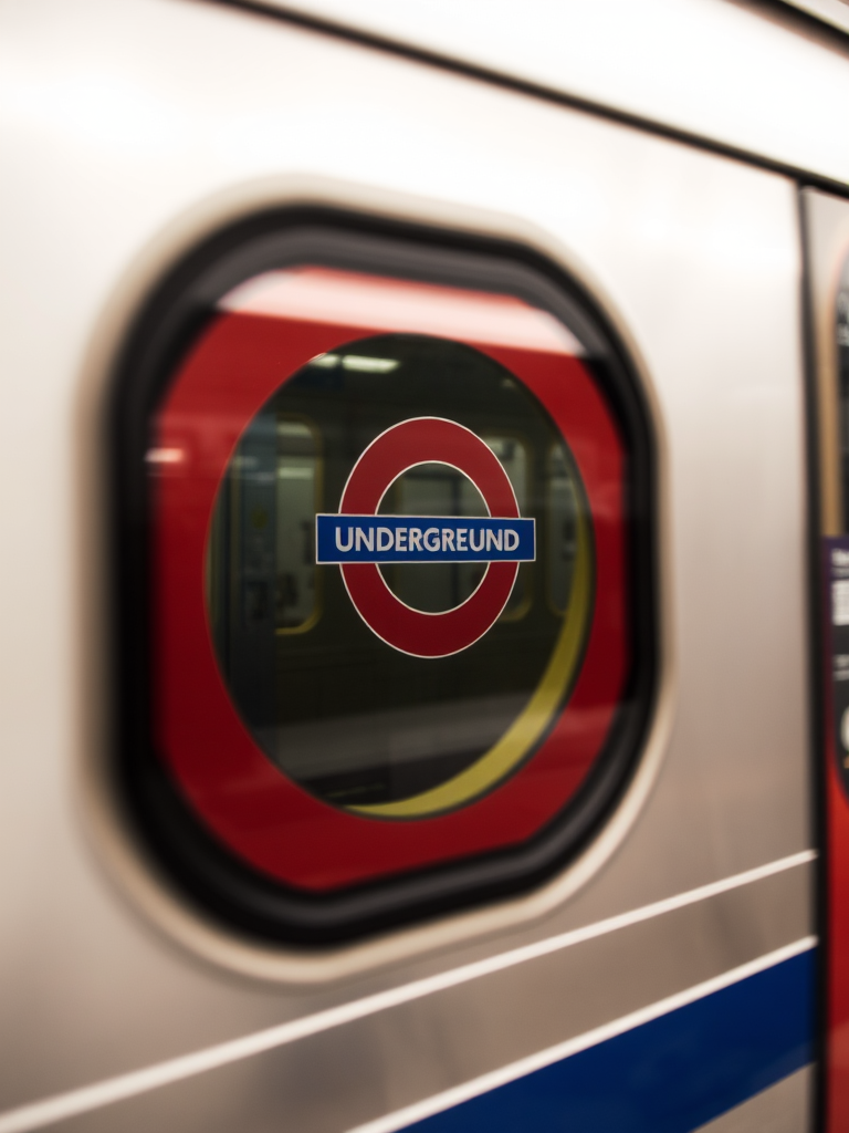 Capture a close-up of a subway train window with a focus on the underground logo, using a DSLR camera, aperture f/2.8, shutter speed 1/60 sec, ISO 400, natural light for clarity and depth.