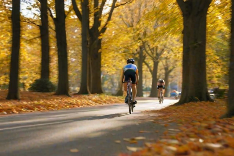 Blurry, fast-paced image of a cyclist racing down a tree-lined road, autumn leaves swirling in the air, soft sunlight filtering through the trees, shadows stretching across the pavement, focus on the determination in the cyclist's face as they speed by.