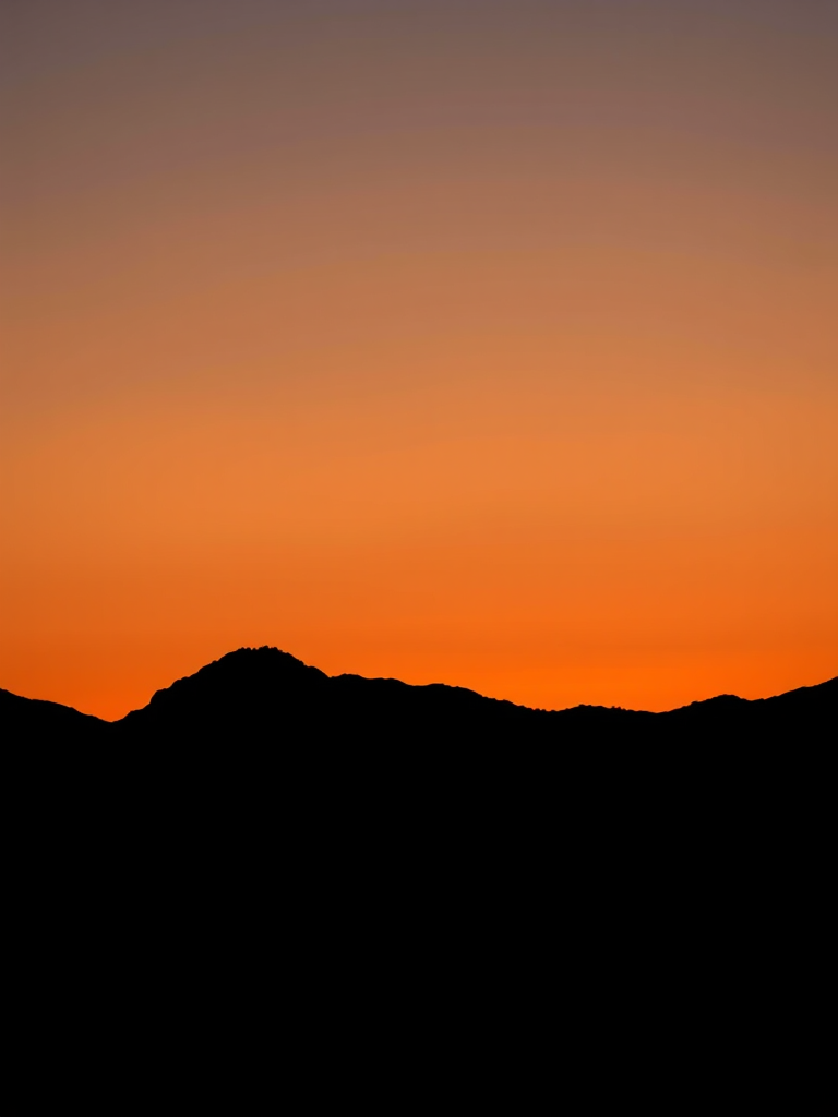 generate a high-quality image of a minimalist black silhouette of a mountain range at sunset, taken with a Canon EOS R5, 50mm lens, aperture f/1.8, ISO 200, shutter speed 1/200s, in landscape orientation, using natural soft lighting.