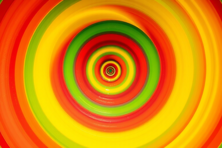 create a vibrant circular spiral pattern with smooth gradient colors transitioning from red to yellow to green to blue, using a DSLR camera with a 50mm lens, aperture set at f/1.8, ISO 100, shot in natural light with a slightly overhead angle to enhance depth.