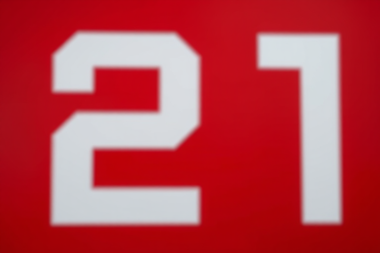 Create an image of a bold white number 21 on a red background with a DSLR camera, 50mm lens, f/1.8 aperture, ISO 100, and a shallow depth of field for enhanced clarity.
