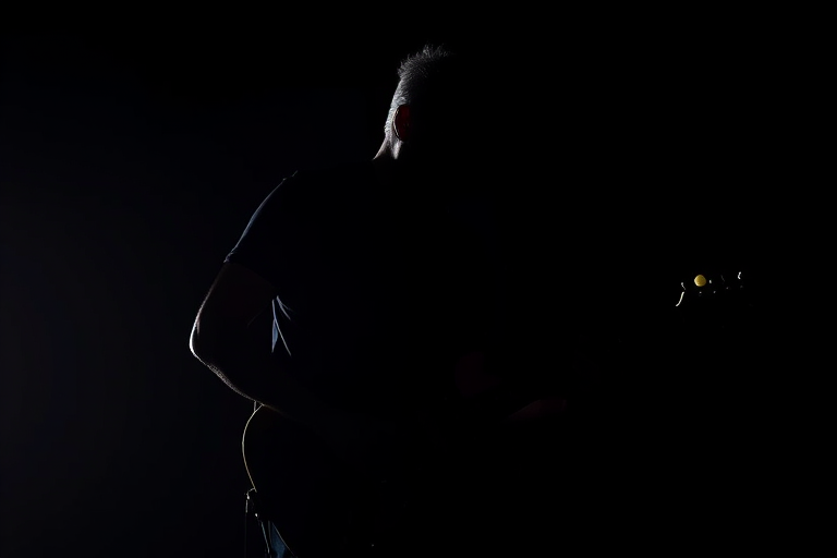 Create a high-contrast silhouette of a guitarist playing an electric guitar against a black background, using a DSLR camera with a 50mm lens, aperture set to f/1.8, ISO 100, and a shutter speed of 1/1000 seconds to capture sharp details and vibrant colors.