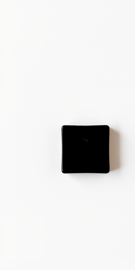 Generate an image of a small black square on a white background, captured with a DSLR camera, aperture set to f/11, ISO 100, using a macro lens with a 50mm focal length, in a top-down view to enhance clarity and sharpness.