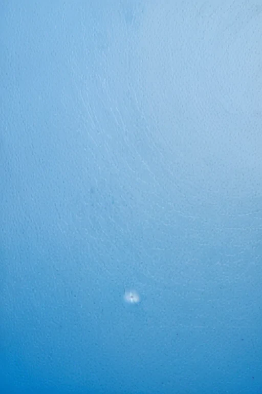 Calm Blue Surface with Subtle Texture and Single Distinct Water Droplet