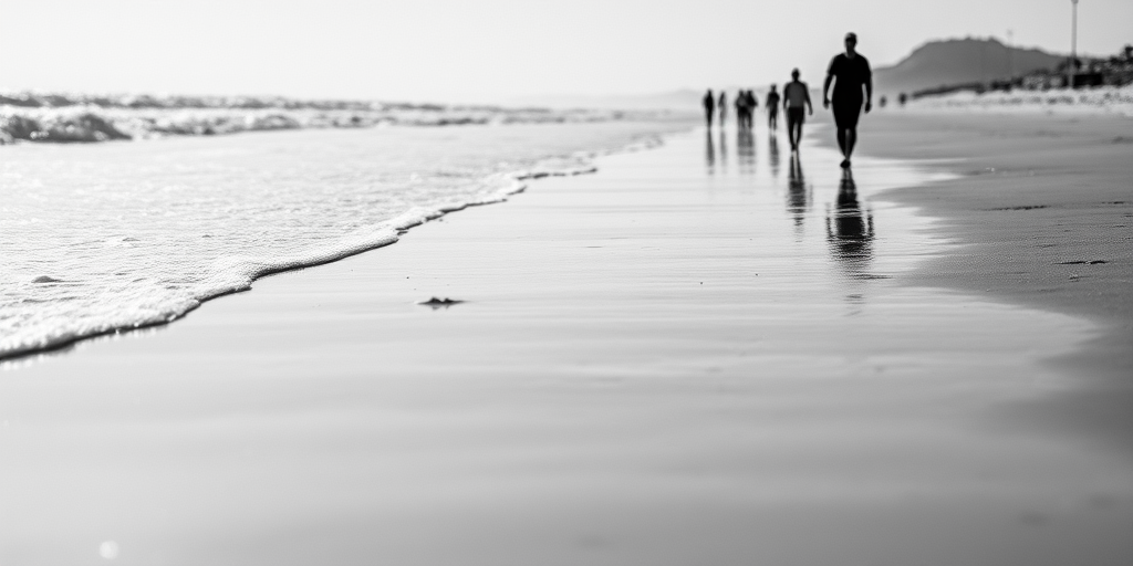beach scene in black and white with people walking along the shoreline, soft waves lapping at the sand, shallow depth of field, 50mm lens, f/2.8, ISO 200, shutter speed 1/125, taken from a low angle to capture reflections in the wet sand, natural light, DSLR camera
