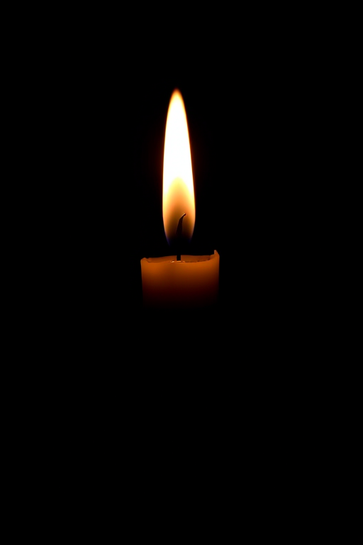 Create a high-resolution silhouette image of a candle with a flame against a black background, shot in macro view using a DSLR camera at f/2.8 aperture, ISO 100, and a shutter speed of 1/60 seconds to enhance detail and contrast.