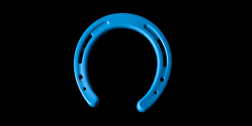 Create a high-resolution image of a blue horseshoe on a black background, using a DSLR camera with a 50mm lens at f/1.8, with a shallow depth of field and soft focus, captured from a slightly elevated angle to enhance the shape and color vibrancy.