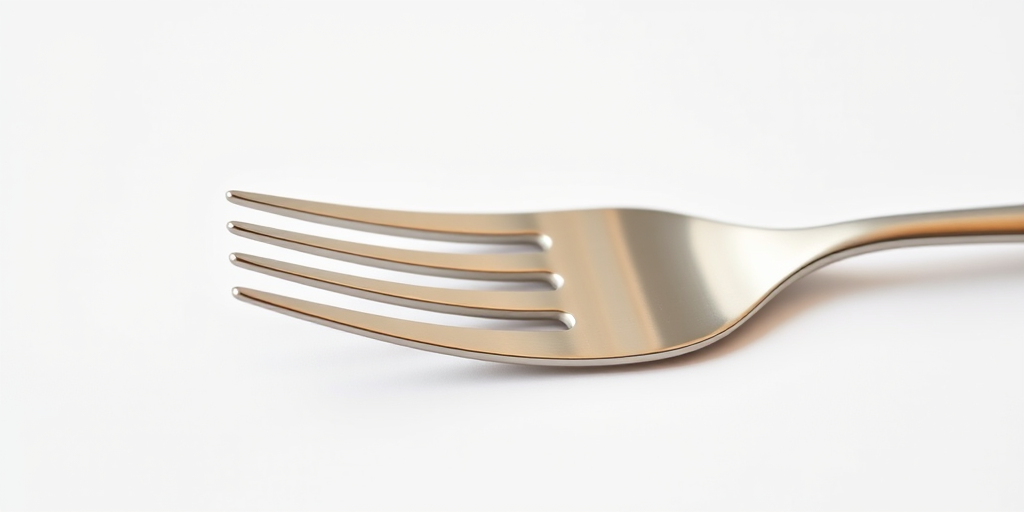 Create a high-resolution image of a stainless steel fork on a plain white background, use a DSLR camera with a 50mm lens at f/2.8 aperture, aperture priority mode, and a shutter speed of 1/125s, ensure soft natural lighting to enhance reflections.