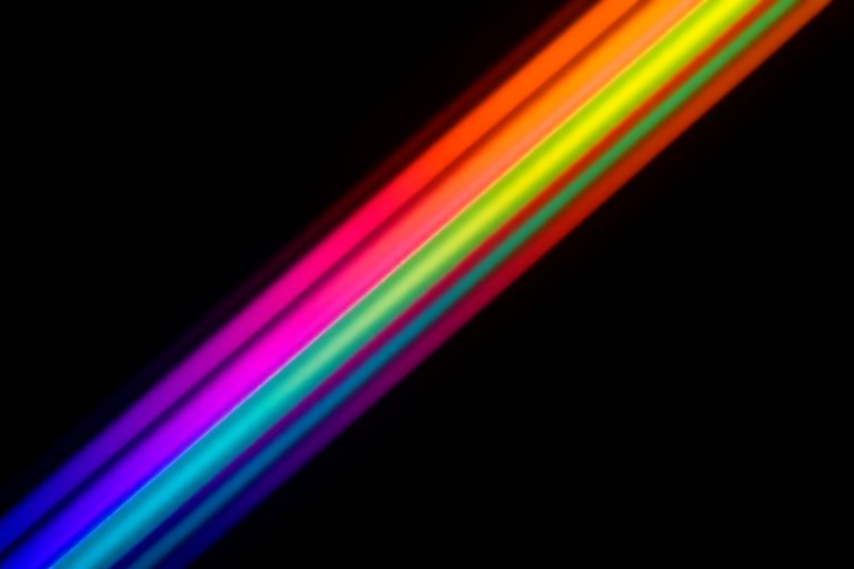create an abstract image of vibrant diagonal rainbow stripes blending softly into a dark background using a Canon EOS R5 with a 50mm f/1.2 lens, aperture set to f/2.8, ISO 100, shot at a shutter speed of 1/125 seconds, in an artistic style with long exposure effect to enhance color blending and light trails.