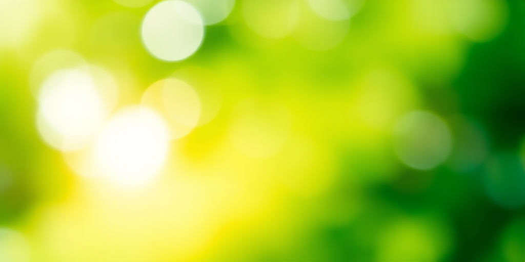 Create a soft focus abstract image with a gradient of vibrant green colors, using a DSLR camera, aperture f/4, shutter speed 1/60, ISO 100, wide-angle lens, shot from a low angle to enhance depth and texture.