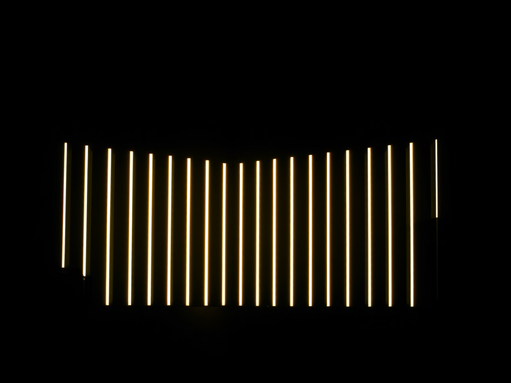 Create a high-resolution image of a series of vertical light bars arranged in an arc against a dark background, captured with a DSLR camera at f/8 aperture, ISO 200, 1/100 sec shutter speed, using a wide-angle lens to enhance depth and detail.