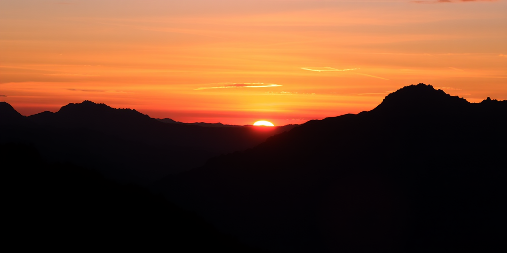 Generate a high-resolution silhouette of a mountain landscape at sunset with vibrant colors, using a DSLR camera with a 50mm lens, aperture set to f/2.8, ISO 100, and a wide-angle view for enhanced depth and detail.
