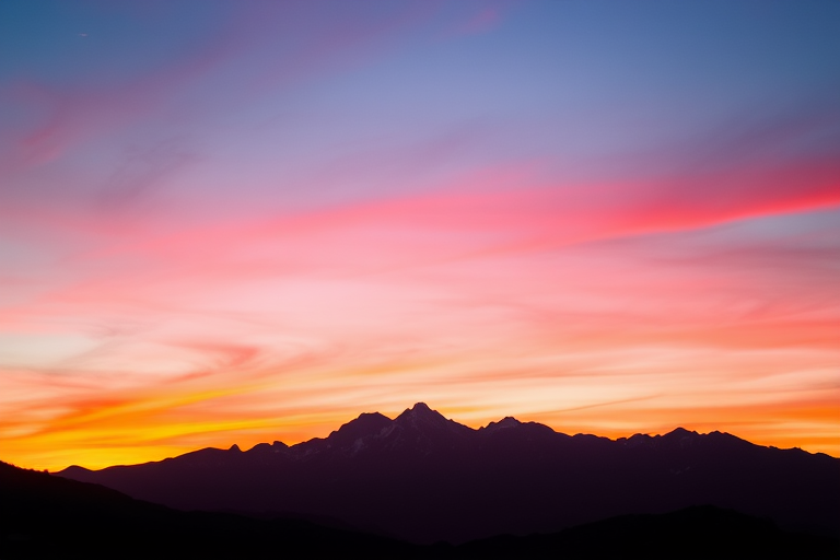 Capture a clear silhouette of a mountain range at sunset with vibrant colors in the sky, using a DSLR camera at f/8 aperture, 1/200s shutter speed, ISO 100, with a landscape view to enhance image quality.
