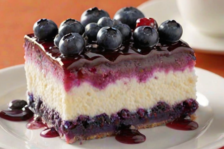 Create an image of a delicious layered dessert showcasing vibrant colors. The dessert should have multiple layers, including a creamy white layer on top with fresh blueberries, a purple berry layer, and a crumbly crust at the bottom. Add a sprinkle of powdered sugar on top for an elegant finish. The setting should be warm and inviting, resembling a cozy café atmosphere.