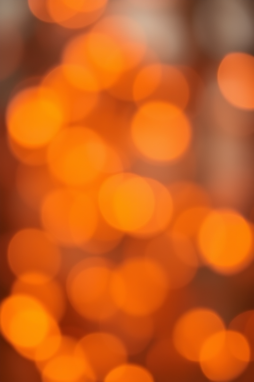 Create a high-resolution image of a soft-focus bokeh background with warm tones of orange and yellow, using a Canon EOS R5 camera, 50mm lens, f/1.8 aperture, ISO 100, and a shallow depth of field for a dreamy effect.