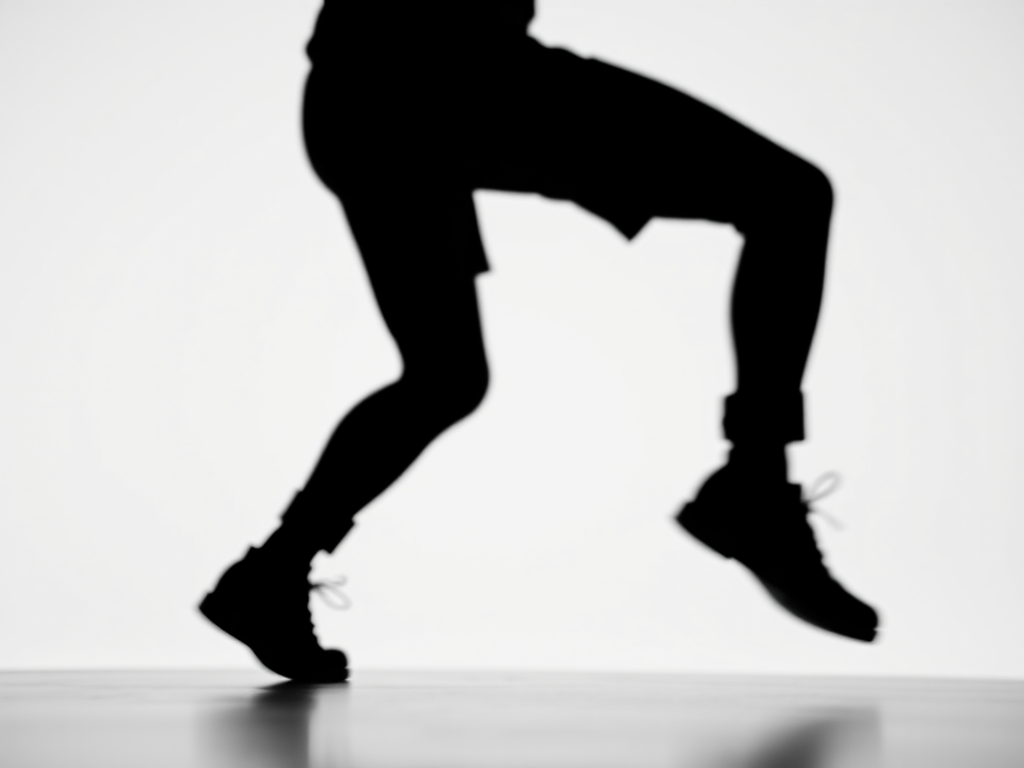 Create a high-resolution image of a stylized black silhouette of a person in a dynamic pose against a plain white background, captured with a Canon EOS R5 at f/2.8, 1/500 sec, ISO 100, using a standard 50mm lens from a slightly low angle to emphasize motion and depth.