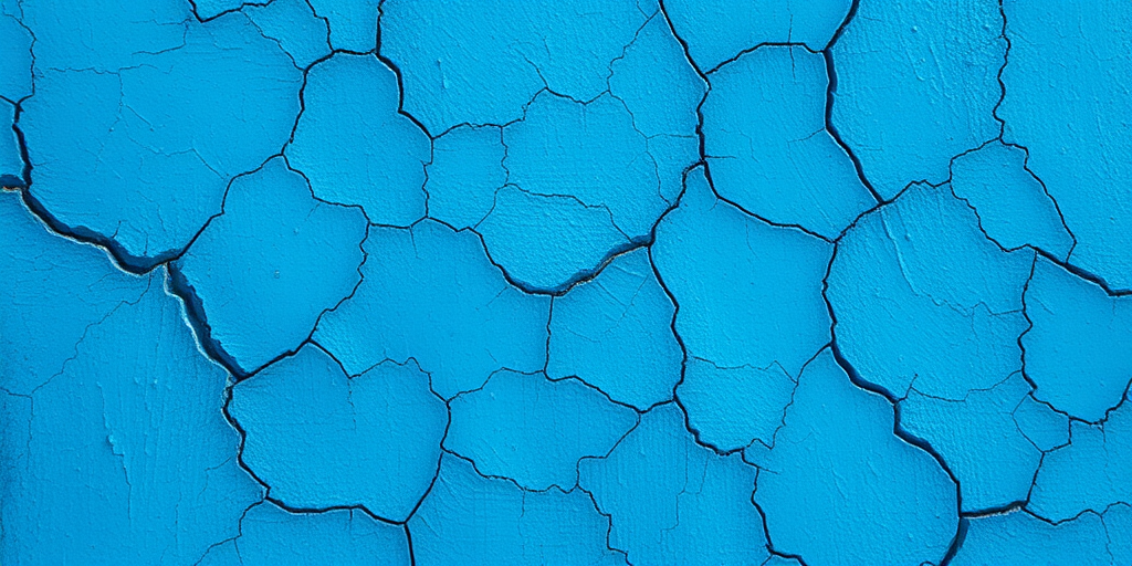 Create a high-resolution image of a textured blue background, featuring intricate cracks and variations in shade, captured with a DSLR camera at f/8 aperture, ISO 100, 50mm lens, shot in natural light from a slight angle to enhance the depth and detail in the texture.
