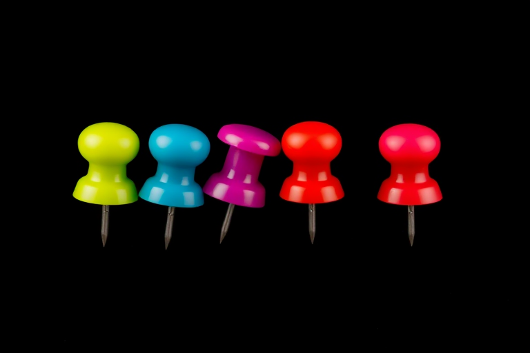 Create a high-resolution vector image of four colorful pushpins in a row, with a clean black background, using a professional DSLR camera with a 50mm lens, f/2.8 aperture, ISO 100, and 1/125 sec shutter speed for enhanced clarity and detail.