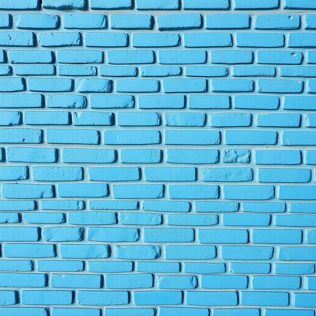Create a high-resolution image of a textured blue brick wall, shot with a DSLR camera at f/8 aperture, ISO 100, and a shutter speed of 1/125s, using a straight-on view and natural daylight to enhance color vibrancy and detail.