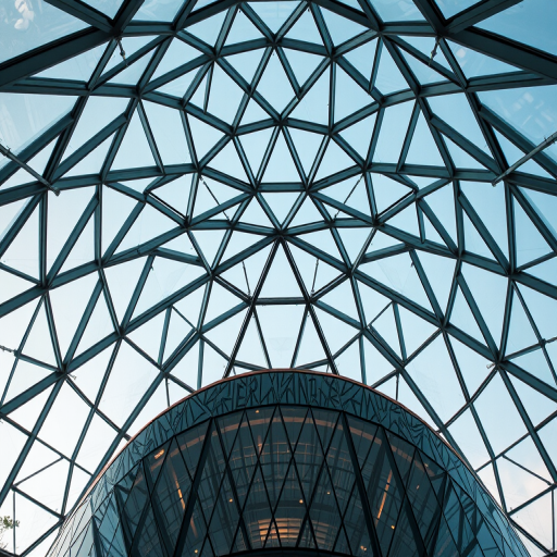 photograph of a modern glass dome with triangular patterns, taken with a Canon EOS R5, 24mm lens, f/8 aperture, ISO 200, natural light, from a low angle to emphasize the architectural design and depth, focus on details of the glass and reflections