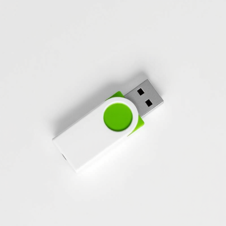 Create a high-resolution image of a modern USB flash drive with a sleek white and green design, shot with a DSLR camera at f/2.8, ISO 100, and a shutter speed of 1/60 sec from an overhead angle in a well-lit studio setting.