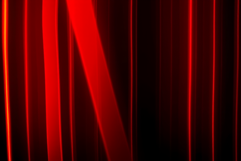 Create an abstract image of vertical red light streaks on a black background with a Canon EOS R5 camera, 50mm lens, f/1.8 aperture, ISO 100, 1/100s shutter speed, using a long exposure style for smooth light diffusion and enhanced contrast.