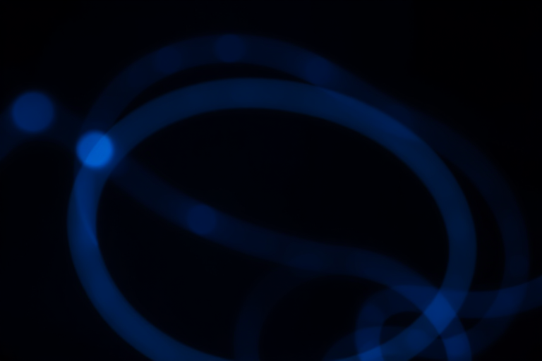 abstract light trails on a dark background with a focus on blue hues, shot with a DSLR camera at f/2.8, ISO 100, 1/60s exposure, using a macro lens for sharp detail and a shallow depth of field to enhance the effects of motion blur and bokeh.