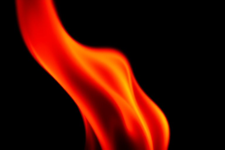 Create a high-resolution image of a stylized red flame with smooth gradients, using a DSLR camera in macro mode, f/4 aperture, 1/200 sec shutter speed, and soft focus background to enhance the flame's details and textures.